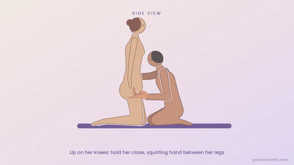 Side view of a woman kneeling upright while her partner kneels close beside her, one arm around her and his squirting hand between her legs